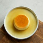 A rich and creamy flan served on a sleek wooden board, perfect for dessert lovers.